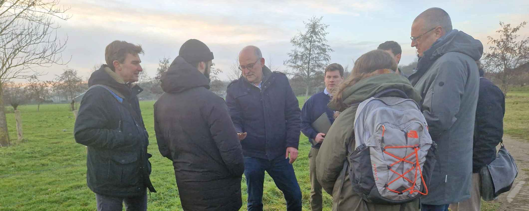 Nick van Eekeren staat met Triodos-medewerkers in de natuur rondom een gegraven gat in de bodem.