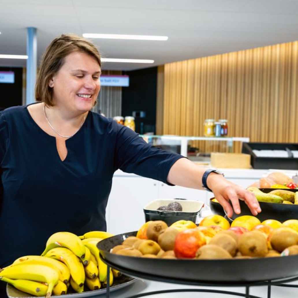 Een mevrouw grijpt naar een appel in een fruitschaal in het Amsterdam UMC.
